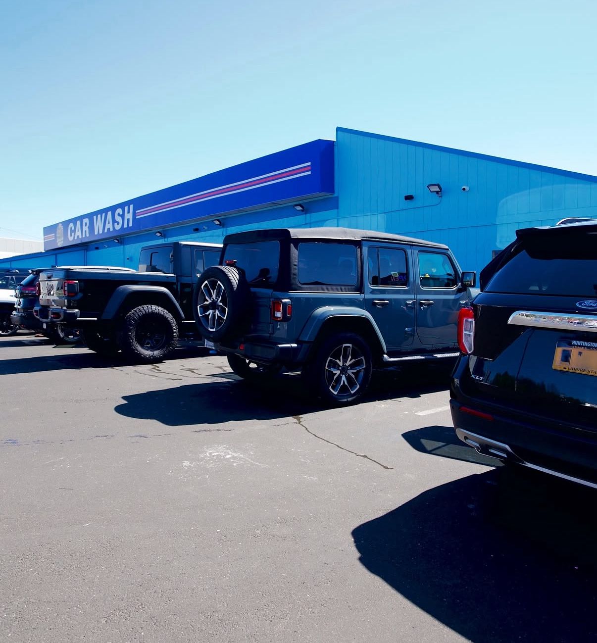 Full-service car wash exterior — blue building, line of cars