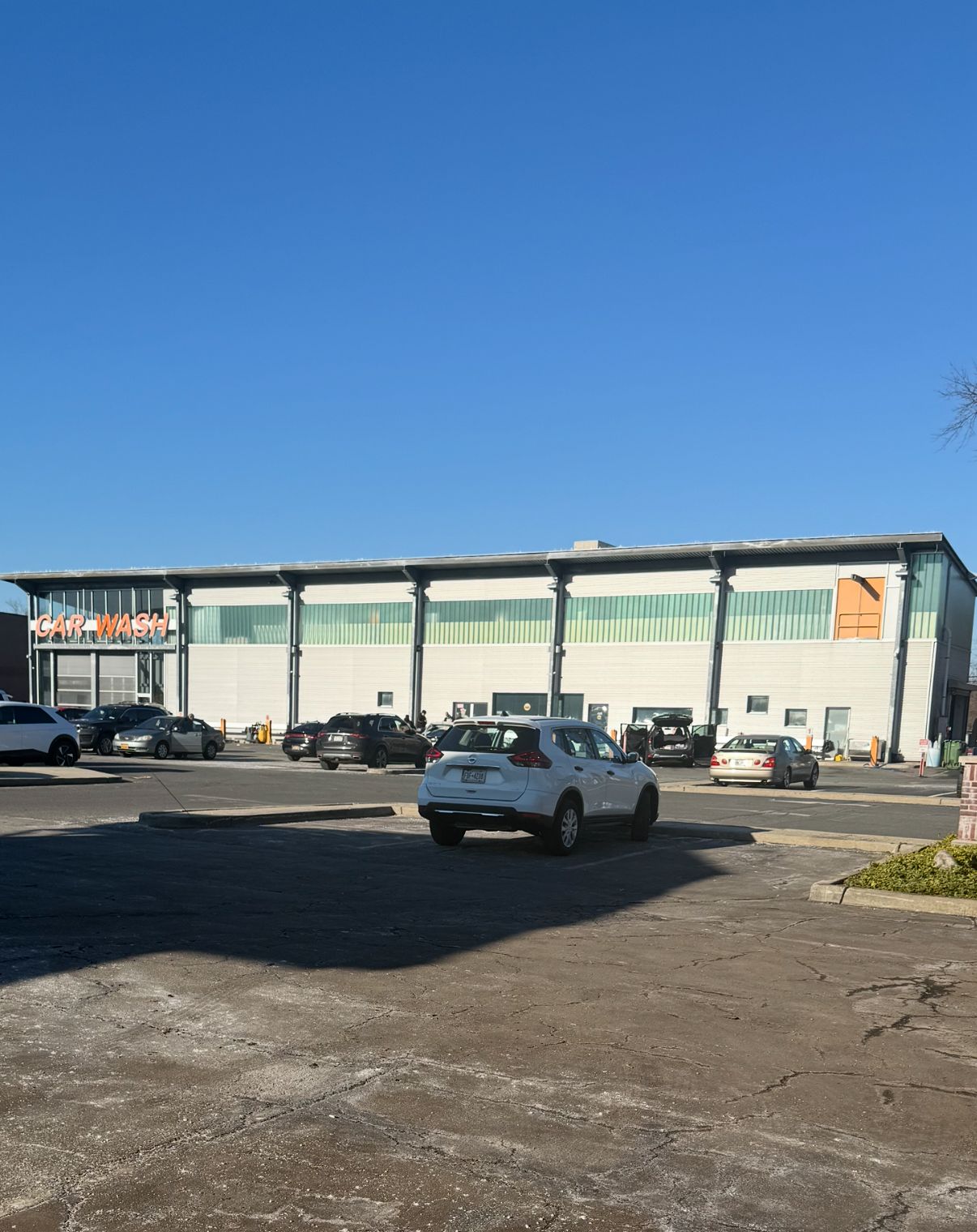 Modernized car wash exterior — white facade, busy lot